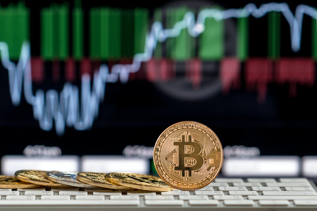 closeup bitcoins mockup on the keyboard over the cryptocurrency trading graph blockchainconsultants